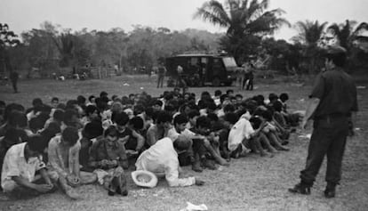 Posseiros rendidos reunidos no campo de futebol do acampamento.