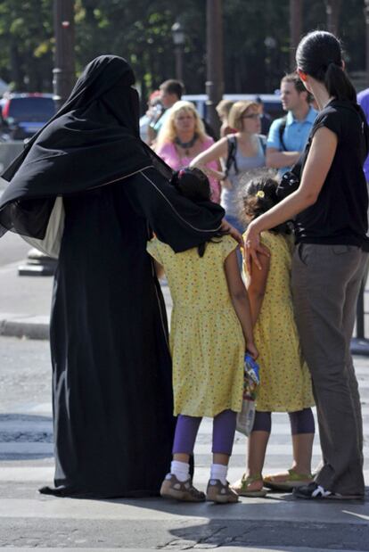 Una mujer con <i>burka</i> pasea con sus hijos en París.