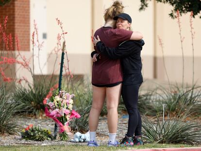 Two residents embrace where flowers were left at the scene of a shooting the day before at Allen Premium Outlets on May 7, 2023 in Allen, Texas.