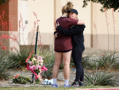 Two residents embrace where flowers were left at the scene of a shooting the day before at Allen Premium Outlets on May 7, 2023 in Allen, Texas.