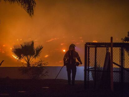 Un bombero intenta proteger una casa en Lilac, cerca de Santa Ana (California).