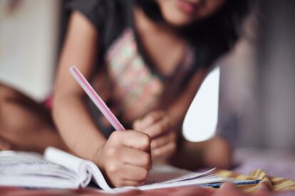 Una niña escribe en un cuaderno escolar, en una foto de archivo.