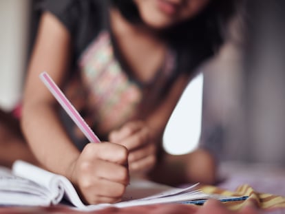 Una niña escribe en un cuaderno escolar, en una foto de archivo.
