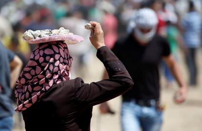 Una mujer palestina lleva una bandeja con piedras en la cabeza durante las protestas palestinas convocadas en la frontera de Israel-Gaza.