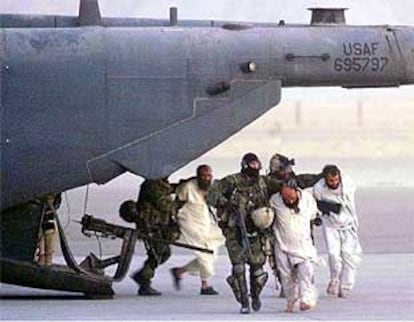 Marines estadounidenses custodian a tres presos afganos, presuntos miembros de Al Qaeda, en el aeropuerto de Kandahar.