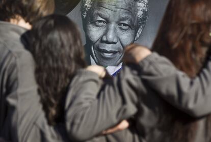 Los miembros del Coro los Niños de Toronto, Ontario (Canadá), se abrazan junto al retrato de Mandela en el exterior del hospital donde permanece ingresado, 13 de julio de 2013. Hasta la fecha, el último parte de la Presidencia, divulgado la semana anterior, indicaba que el estado de Mandela -hospitalizado desde el pasado 8 de junio por la recaída de una infección pulmonar- era "crítico pero estable" y que respondía bien al tratamiento.