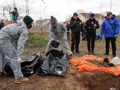 Forenses ucranios colocan en bolsas para cadáveres restos quemados de civiles exhumados en Bucha, en abril.