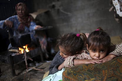 Dos niñas descansan mientras su madre hace la comida durante un día lluvioso en la localidad cisjordana de Beit Lahiya (Palestina), 5 de diciembre de 2013.