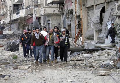 ATTENTION EDITORS - VISUAL COVERAGE OF SCENES OF INJURY OR DEATH 

People walk as they carry a dead body in the besieged area of Homs February 9, 2014. Six hundred people left the besieged ruins of rebel-held central Homs on Sunday, escaping more than a year of hunger and deprivation caused by one of the most protracted blockades of Syria's devastating conflict. The evacuees, mainly women, children and old men, were brought out by the United Nations and Syrian Red Crescent on the third day of an operation during which the aid convoys came under fire and were briefly trapped themselves in the city. Picture taken February 9, 2014.
REUTERS/Thaer Al Khalidiya (SYRIA - Tags: POLITICS CIVIL UNREST CONFLICT)