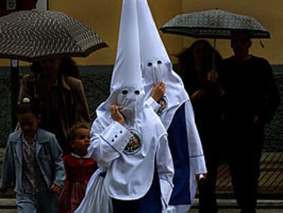 Dos nazarenos de la hermandad de Los Negritos, una de las cinco cofradías que decidieron no salir ayer en Sevilla por la lluvia.