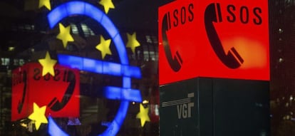 El s&iacute;mbolo del euro, reflejado en un cristal frente a un tel&eacute;fono de emergencia en Fr&aacute;ncfort