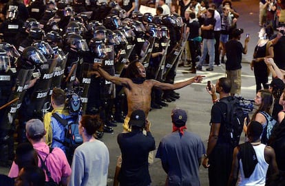 Uno de los protestantes (c) grita al resto de manifestantes mientras los policías de Charlotte-Mecklenburg hacen guardia tras él, en Charlotte, Carolina del Norte. 