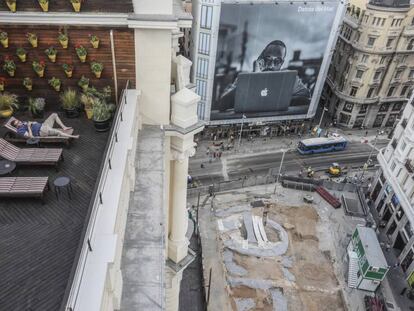 Un vecino de Madrid disfruta del verano en una terraza desde la que ven las obras en la estación de metro de Gran Vía.