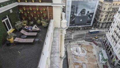 Un vecino de Madrid disfruta del verano en una terraza desde la que ven las obras en la estación de metro de Gran Vía.