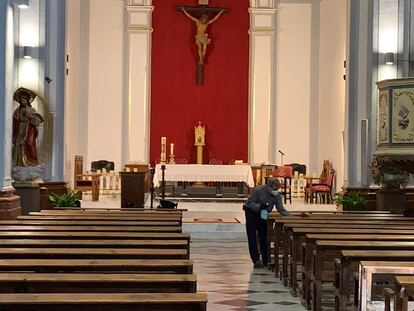 El párroco de Utiel, Agustín Alcayde, desinfecta los bancos de la iglesia.