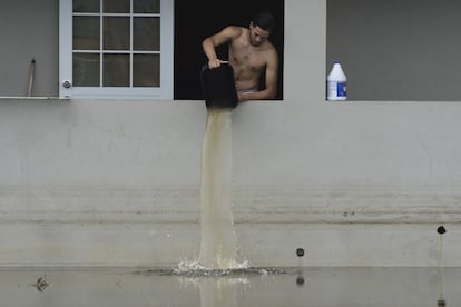 Un residente local achica agua de su casa inundada tras el paso del huracán María en Catano (Puerto Rico).