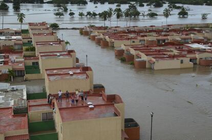 Gente en la azotea de una casa en un barrio inundado después de la tormenta tropical.