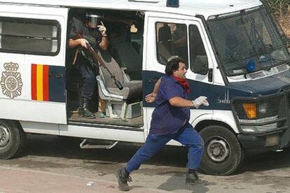 Un empleado de Izar corre delante de un coche de la policía.