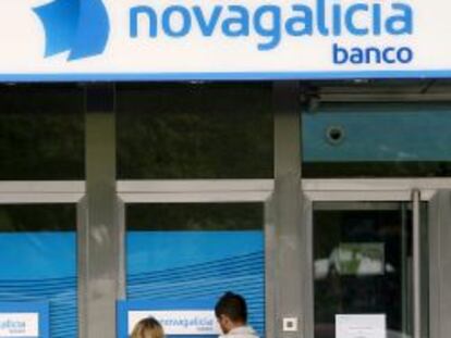 Dos j&oacute;venes retiran dinero de un cajero en una sucursal de Novagalicia Banco. 