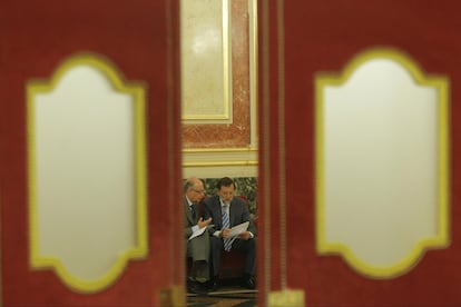 El presidente del PP, Mariano Rajoy, charla con Cristóbal Montoro, portavoz de economía de su partido, en una sala del Congreso.