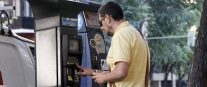 Un usuario saca un tique en un parquímetro nuevo con el viejo al fondo.