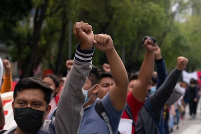 Jóvenes gritan consignas mientras alzan sus puños al aire en señal de protesta.