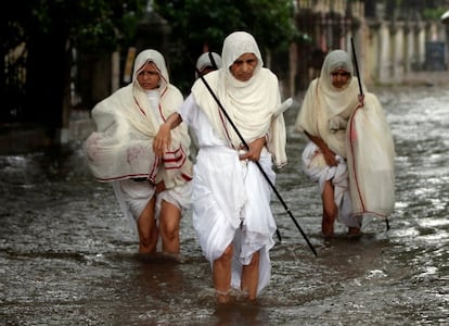 Mujeres de la comunidad Jain caminan a través de una calle anegada después de fuertes lluvias en Ahmedabad (India).