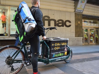 Un repartidor Fnac de envíos de pedidos ecológicos frente a una tienda en Madrid.