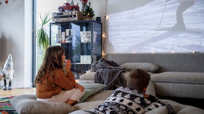 unos niños viendo una peli en el proyector en la pared de su casa.