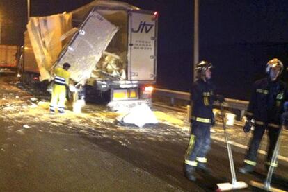 Los bomberos retiran durante toda la noche la pintura vertida sobre la carretera tras la colisión entre los dos camiones.