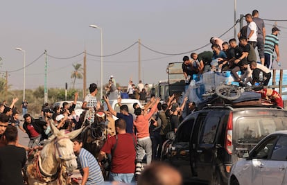 Varios hombres reparten agua para las familias palestinas que se desplazan del norte de la franja de Gaza hacia el sur, este jueves.