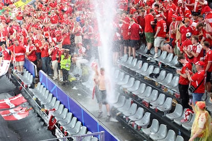 Dos seguidores daneses se mojan en una cascada de agua formada tras las fuertes lluvias caídas durante el partido. 