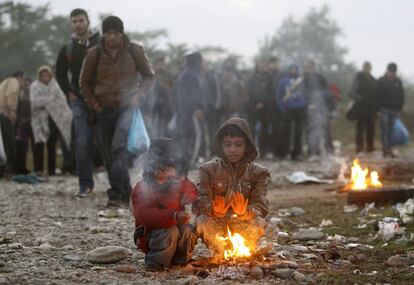 Dos niños se calientan junto a una hoguera cerca de la ciudad de Gevgelija (Macedonia), en la frontera con Grecia. La Federación Internacional de Cruz y Media Luna Roja (IFRC) ha reclamado una ayuda "vital" para los refugiados atrapados en los Balcanes por el cierre y los controles en las fronteras, que quedarán aún más expuestos ante la llegada del invierno.