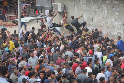 Palestinos desplazados intentan acceder a una panadería donde se distribuye pan en el campo de refugiados gazatí de Nuseirat, este jueves.