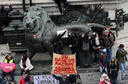 Los manifestantes se acercan y cuelgan carteles en uno de los leones de la plaza de la República en París, durante una nueva jornada de manifestaciones.