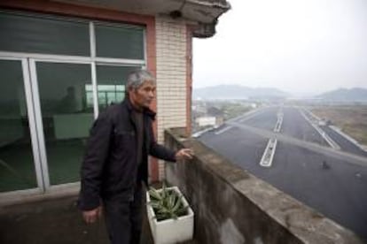 Luo Baogen, due?o de una casa de cinco pisos que permaneca en medio de una avenida en construccin en la ciudad de Wenling (China), asomndose en un balcn del inmueble. EFE/Archivo