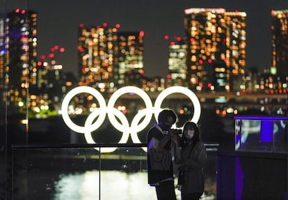 Una pareja se toma un selfi antes los anillos olímpicos en Tokio.