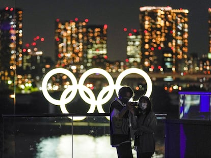 Una pareja se toma un selfi antes los anillos olímpicos en Tokio.