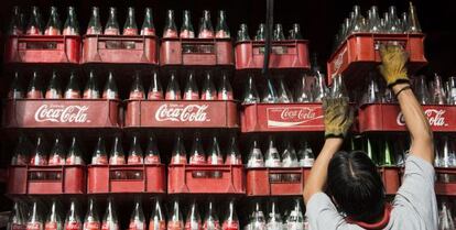 Un trabajador apila cajas vacías de botellas de Coca-Cola en México.