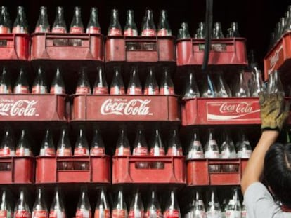 Un trabajador apila cajas vacías de botellas de Coca-Cola en México.