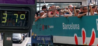 Turistas en un BusTurístic en Barcelona junto a un termómetro que marca 37 grados de temperatura