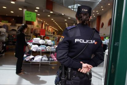 Fátima realiza unas compras, mientras los policías vigilan a las puertas del establecimiento.