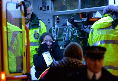 Una mujer llora dentro de una ambulancia mientras es atendida por personal sanitario.