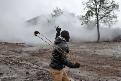 Una persona lanza una piedra con una honda hacia la nube de gases lacrimógenos donde se encuentran agentes de la Policía de Kenia, este jueves 26 de octubre de 2017. Se han producido duros enfrentamientos entre policías y ciudadanos en el barrio marginal de Kibera (a las afueras de la capital), para intentar boicotear las elecciones.