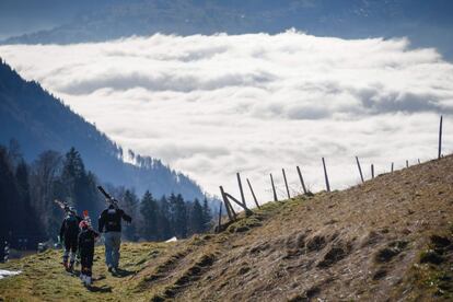 Una familia pasea con su esquíes sobre una colina sin nieve en la estación de los Alpes suizos de Leysin.