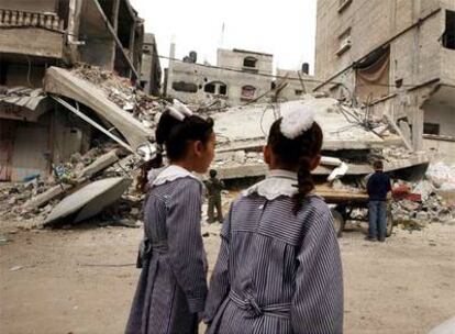 Dos niñas con uniforme escolar observan un edificio destruido en Beit Lahiya, Gaza.