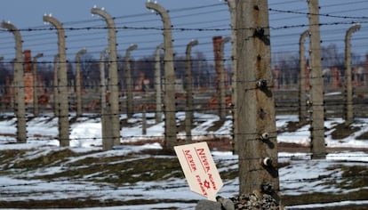 Una placa que dice “Nunca de nuevo, nunca olvidar” se levanta en unas piedras junto a la verja del campo de Auschwitz-Birkenau.