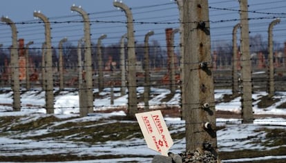 Una placa que dice &ldquo;Nunca de nuevo, nunca olvidar&rdquo; se levanta en unas piedras junto a la verja del campo de Auschwitz-Birkenau.