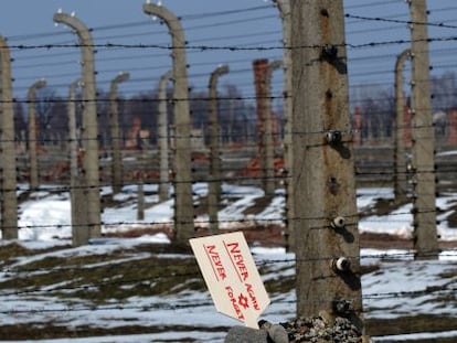 Una placa que dice &ldquo;Nunca de nuevo, nunca olvidar&rdquo; se levanta en unas piedras junto a la verja del campo de Auschwitz-Birkenau.