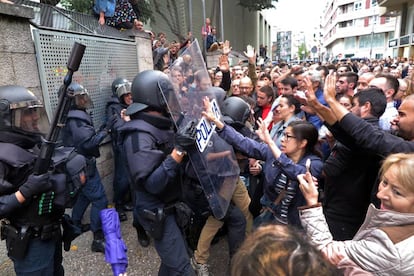 Votantes de un colegio electoral de Girona forcejean con agentes antidisturbios de la Polic&iacute;a Nacional que acudieron a clausurar el centro e incautarse de las urnas.
 